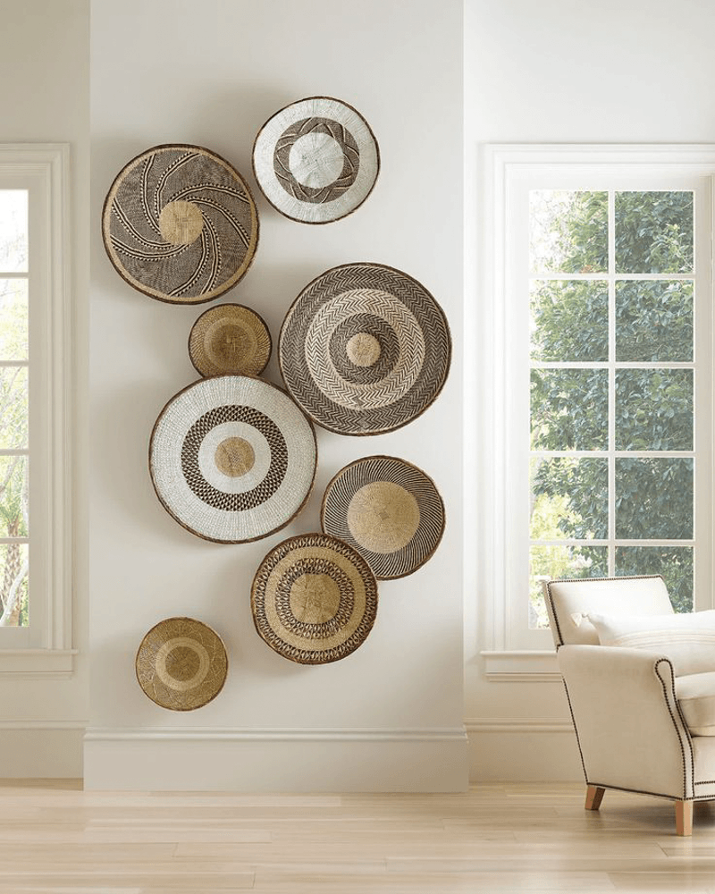 Unique wall decor idea between two windows with a floor to ceiling arrangement of round wicker objects hanging on the wall 