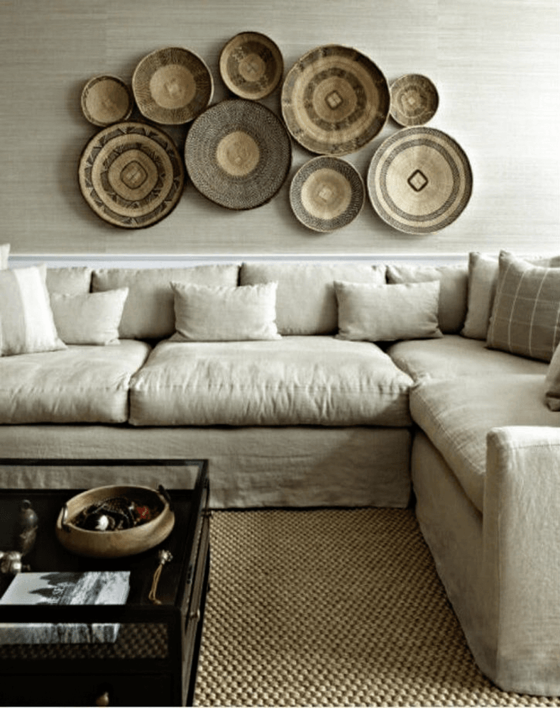 Wall art idea for living room with a gallery wall of woven baskets hanging above a neutral color sectional