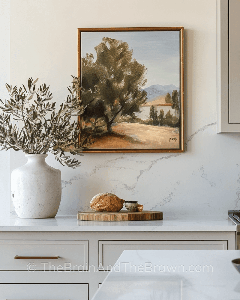 A landscape piece of artwork hangs above a kitchen countertop