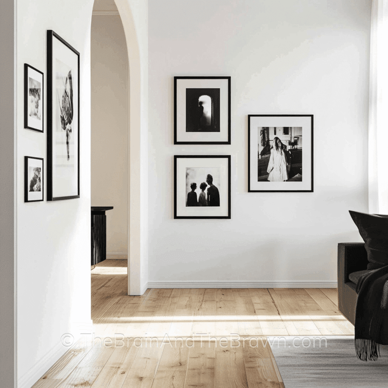 A living room wall decor idea with white walls and a gallery wall of black and white photography in black frames hangs on two walls. 