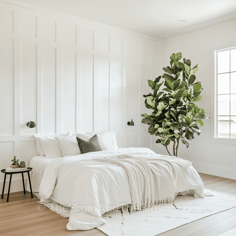 Wall panelling idea for bedroom with floor to ceiling wall panelling painted white with two wall sconces on each side of a king size bed and a large indoor tree in the corner