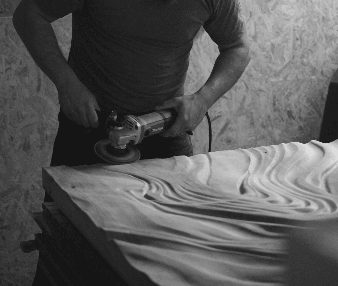 An artist works on a piece of wood wall art 