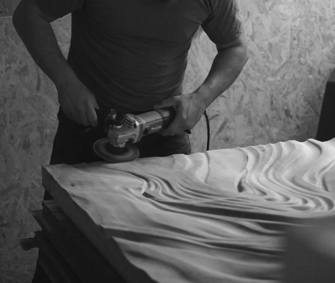 An artist works on a piece of wood wall art 