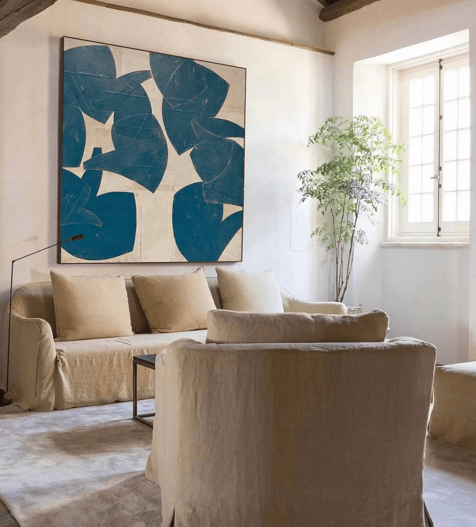 Large piece of blue and beige abstract wall art for bedroom idea with beige couch below it