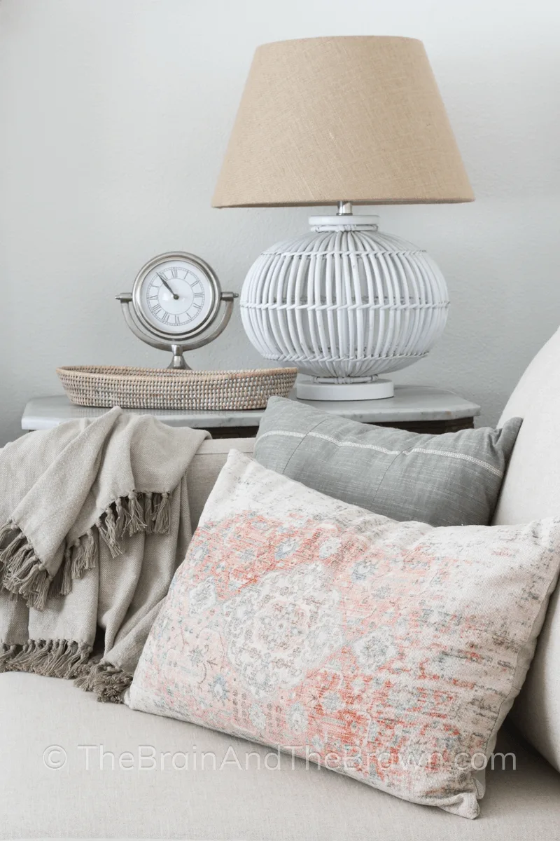 Antique pillow on a corner of a couch with a lamp on the table next to it