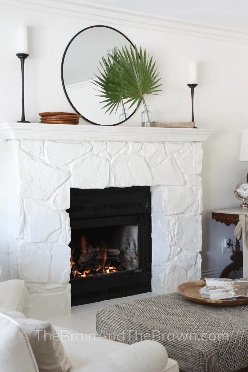 Fireplace in living room with painted white stone and minimally decorated fireplace mantel