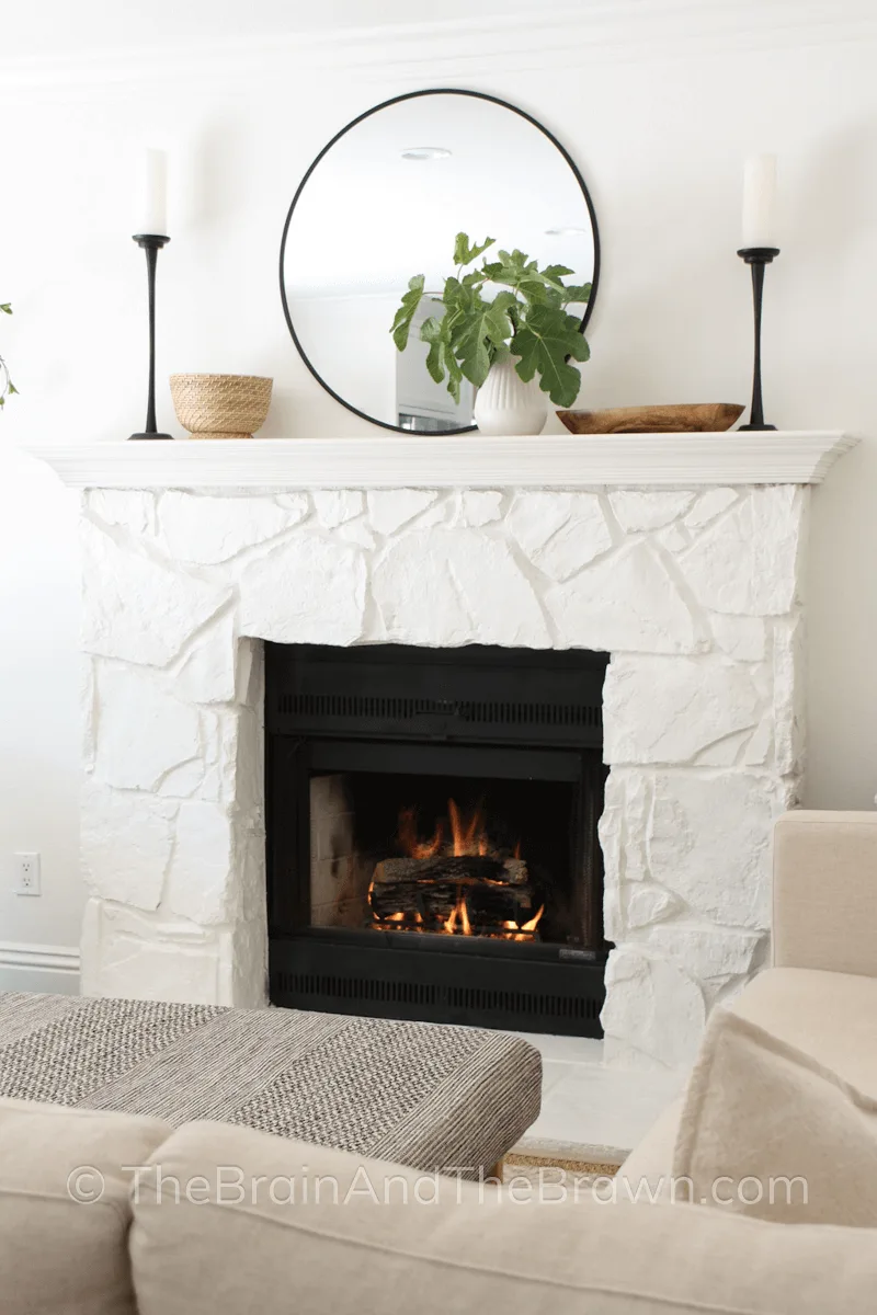 White painted stone fireplace with a mirror and candle sticks