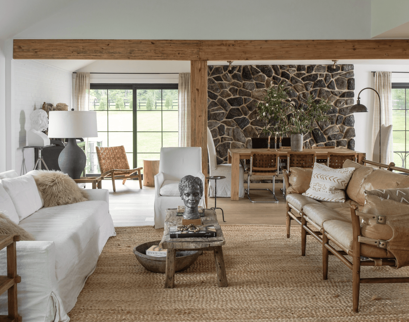 An open concept living room and dining room with a stone fireplace wall idea on the back wall behind the dining table