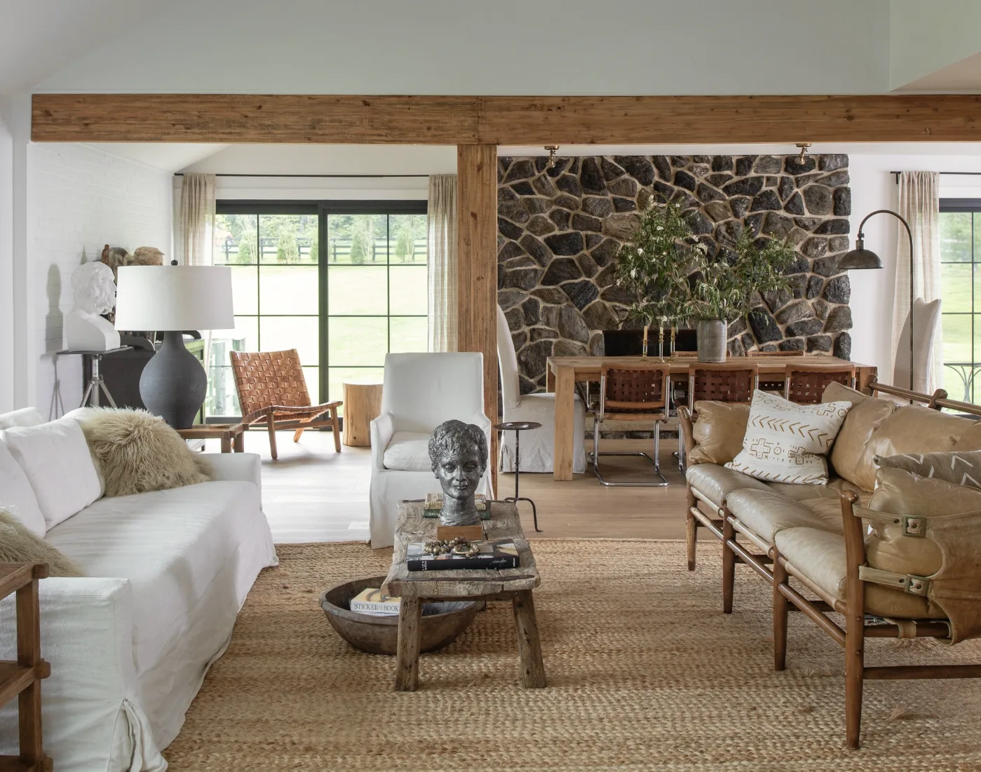 An open concept living room and dining room with a stone fireplace wall idea on the back wall behind the dining table