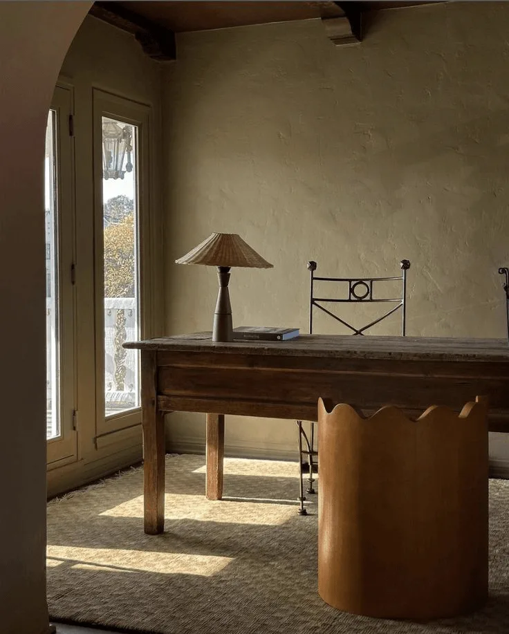 Mediterranean-style plaster wall office with antique desk and sculptural chairs