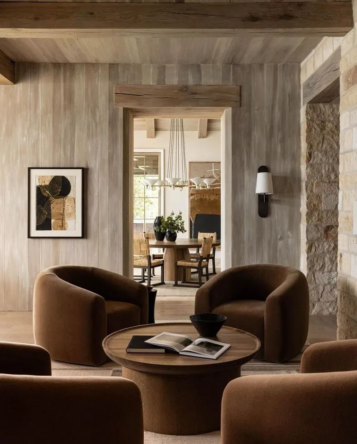 large soft brown armchairs in home office with stone walls, modern and cozy