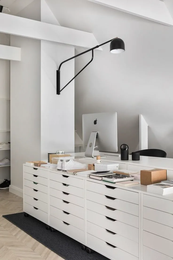 a black and white home office with white ikea storage drawers and black wall sconce