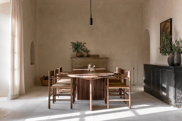 a spanish-style dining room with wood furniture and plaster walls