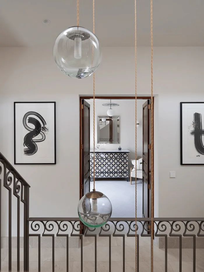 home interior hallway with staircase looking into bathroom in a modern traditional, transitional style with black and white and brass lighting