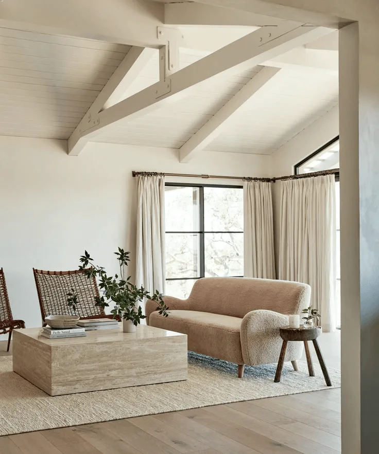 a warm white living room with modern travertine coffee table, white ceiling beams, in a modern decor
