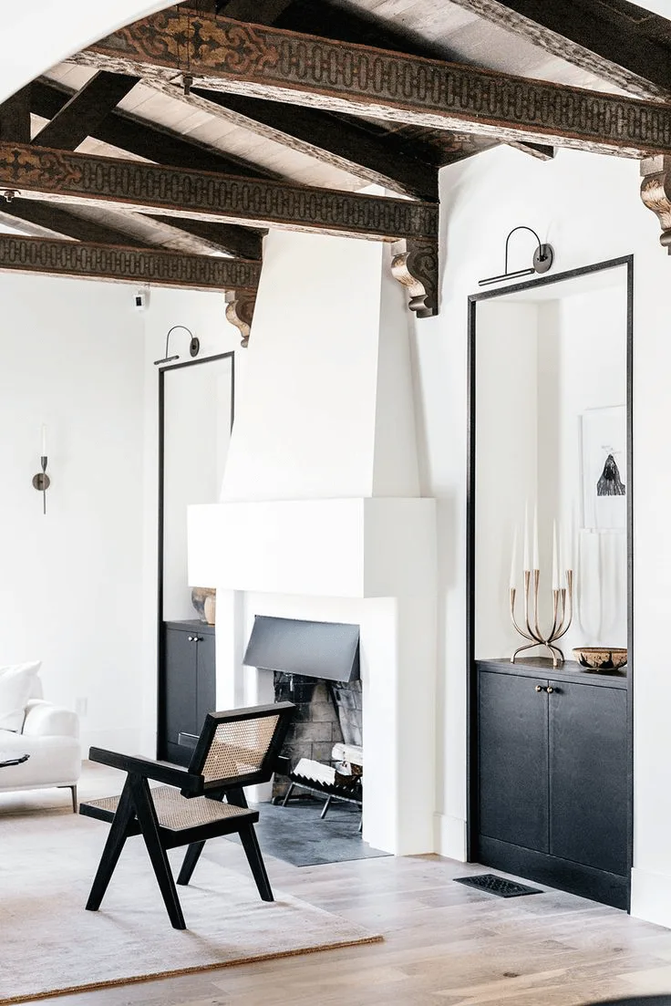 a modern Spanish-style black and white living room with fireplace and bookshelves built-in