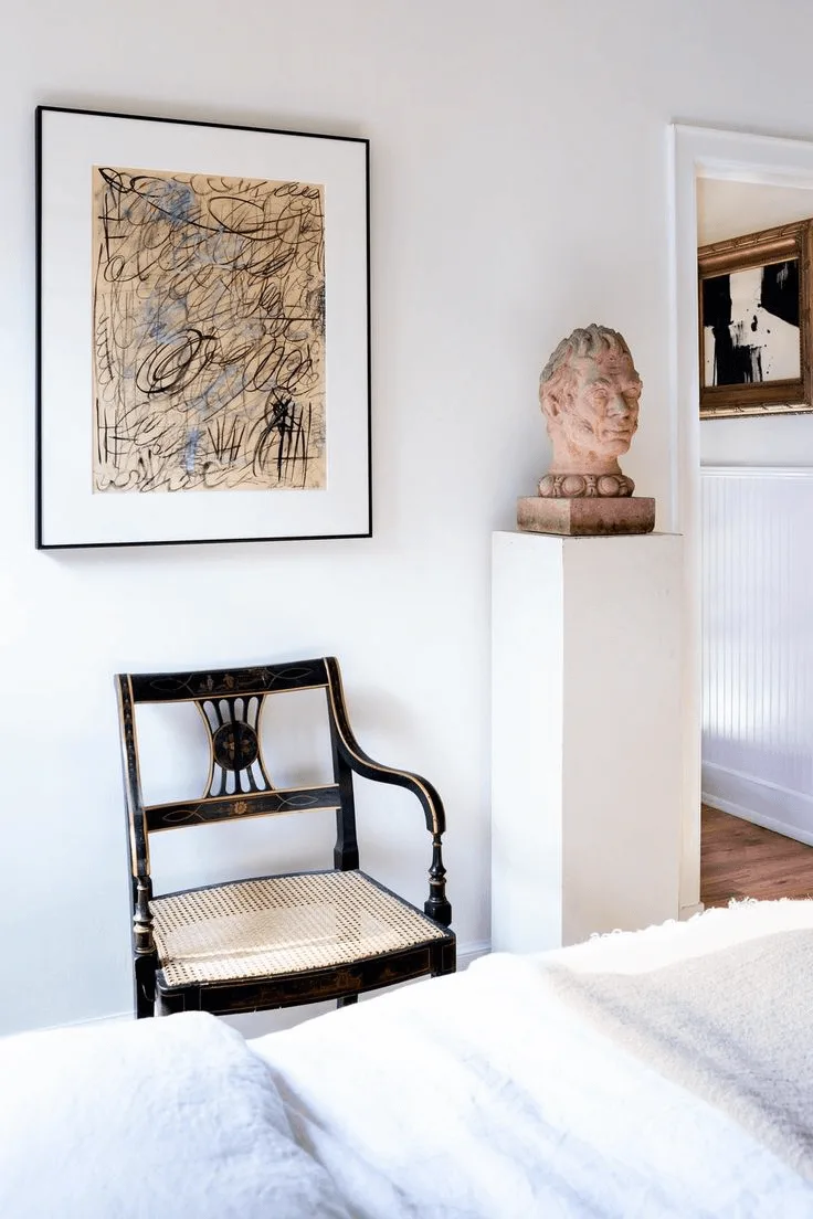 a wall with Regency traditional chair, modern artwork and sculpture on a pedestal