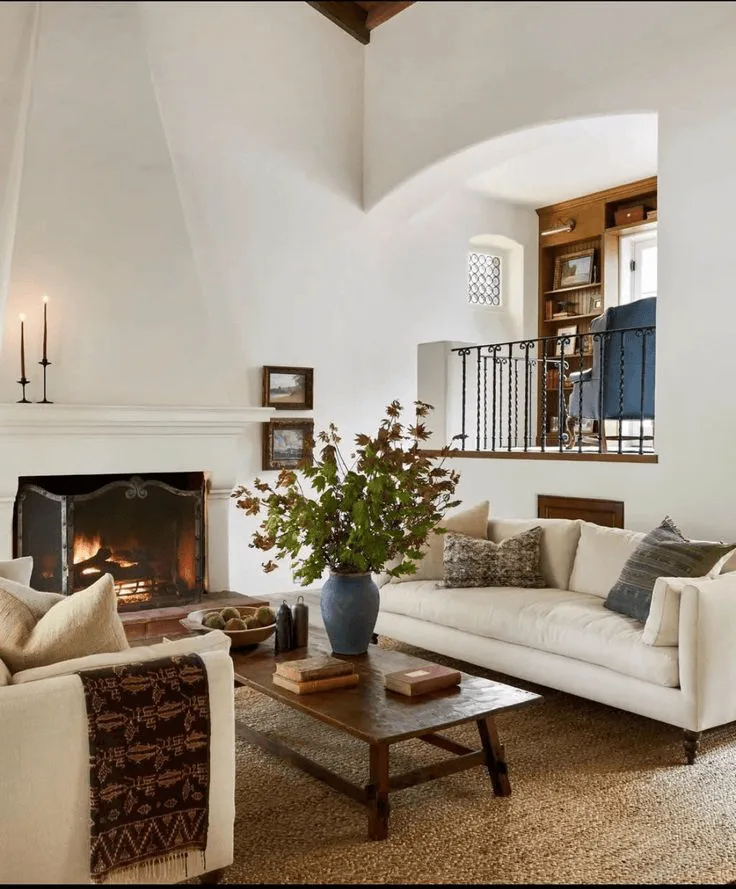 a living room with white plaster fireplace and modern cozy furniture in Spanish style