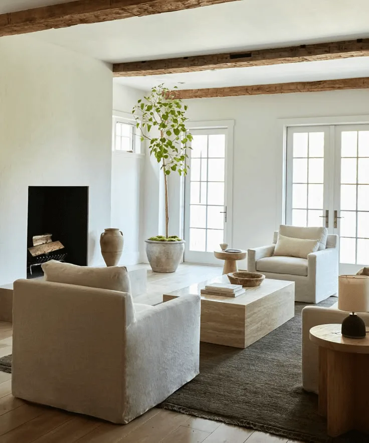 a home interior, living room with white plaster fireplace and wood ceiling beams, marble coffee table