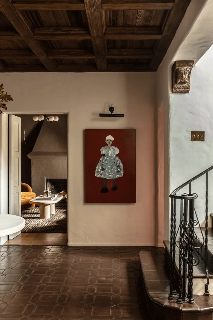 a Spanish-style house interior design showing an entryway with tile floors, Spanish artwork, stairs
