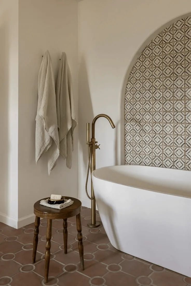 a Spanish-style bathroom interior in a house with tile on walls, tub, and tile floors