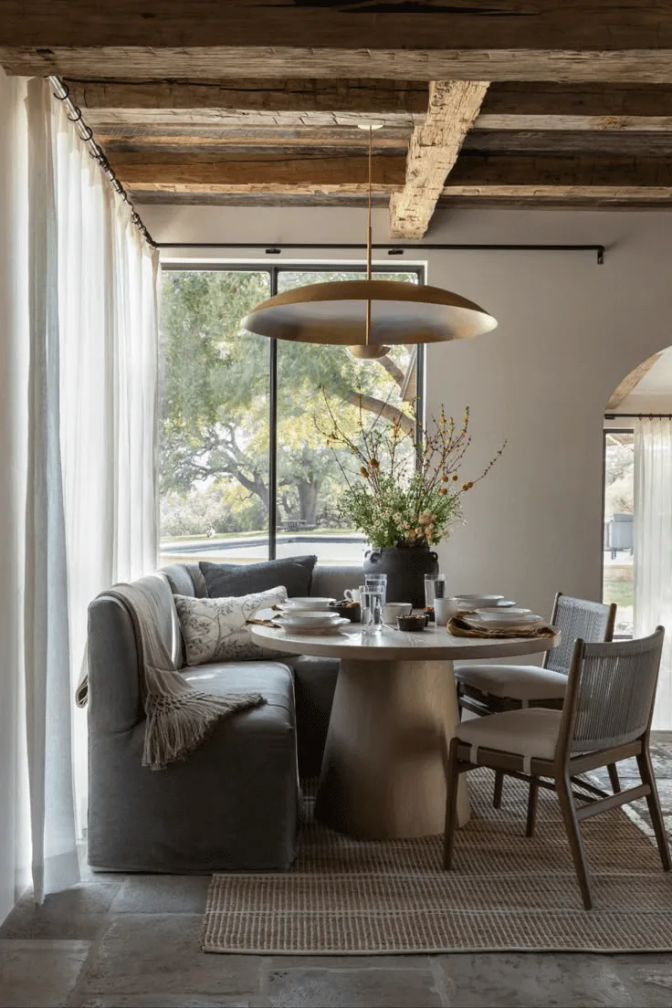 a Spanish-Revival style dining room with banquette, wood ceiling beams, and brass pendant hanging chandelier 