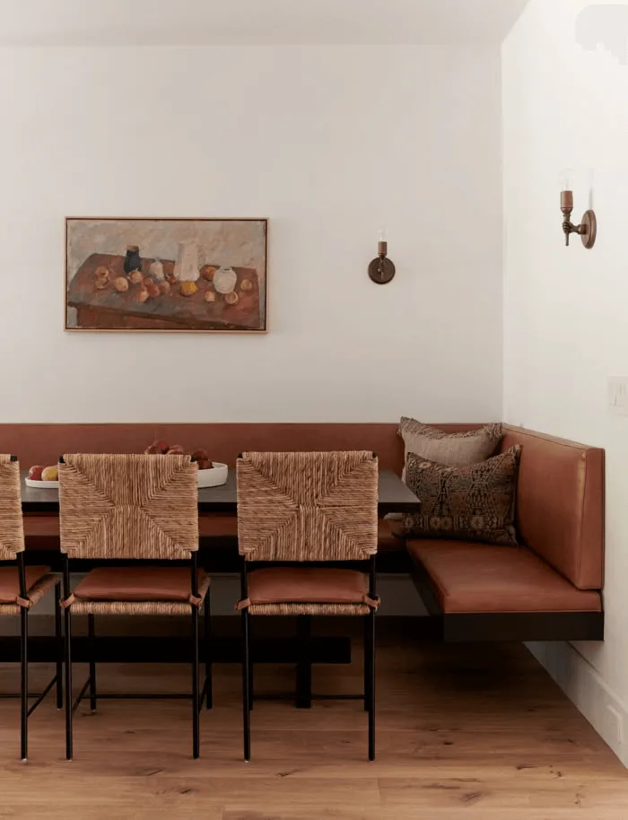 a Spanish-style banquette with leather and woven chairs, sconces and art