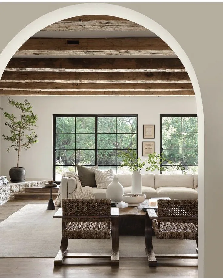 a modern Spanish Revival style house interior design with arched doorway, large wood beams, black windows