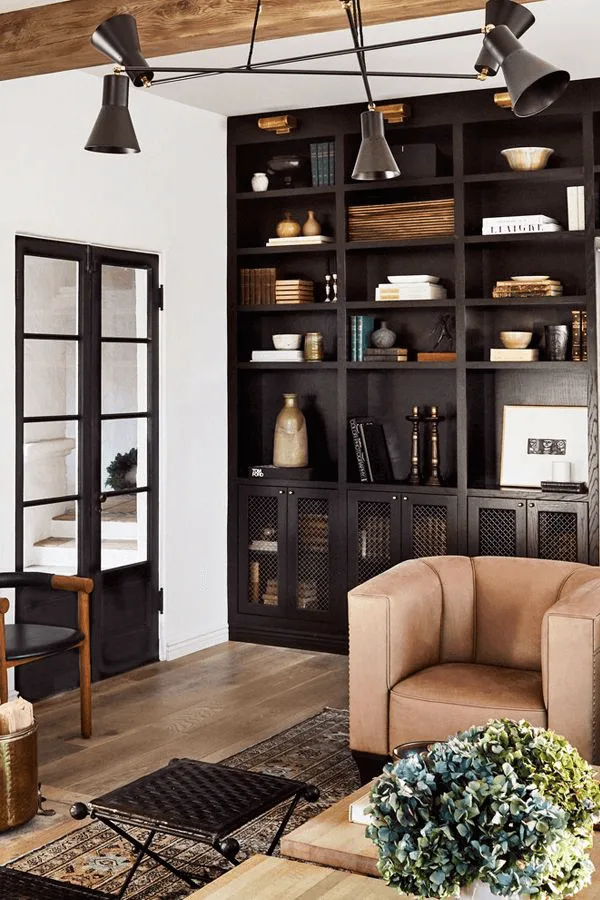 a Spanish style decor living room with black built in bookshelves