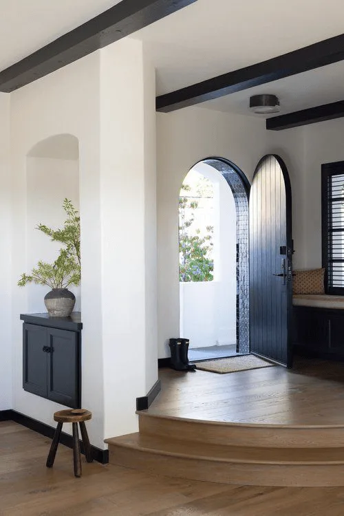 a Spanish-style house entryway with arched door and hardwood floors