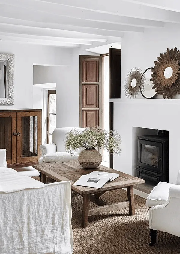 a white hacienda-style home interior, living room with white plaster fireplace and white wood ceiling beams