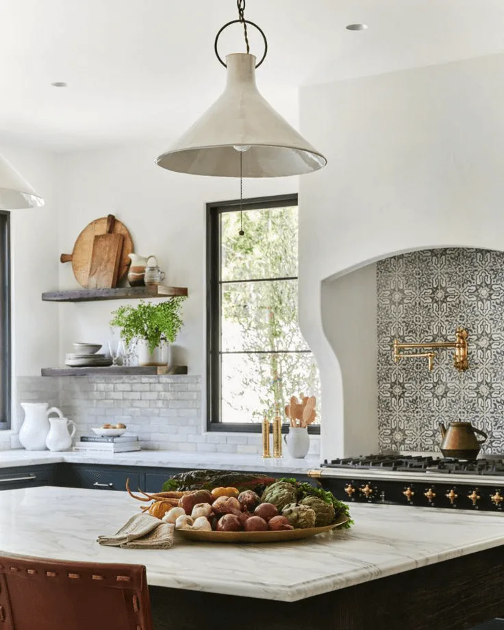 a white kitchen in Spanish style with tile backsplash behind stove and a large island