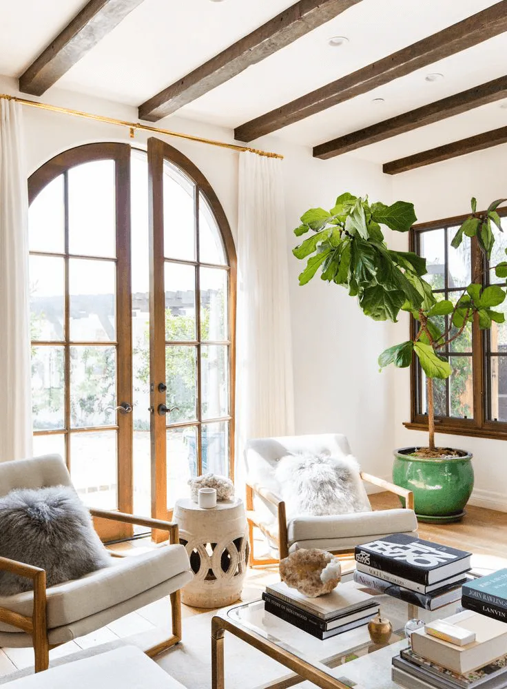 a Spanish-style living room with arched wood French doors and beams on ceiling