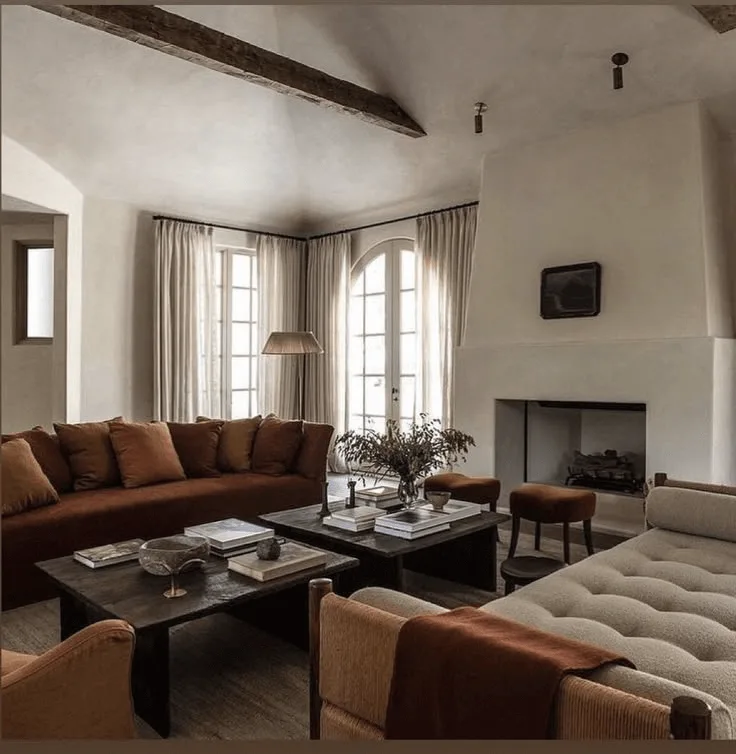 a Spanish hacienda-style house interior, living room with white plaster fireplace, two coffee tables and wood ceiling beams