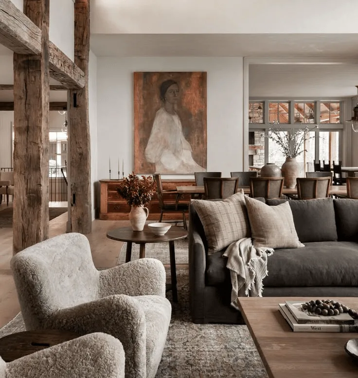 a Spanish-revival style living room with boucle chair, large wood beams, and large wall art of a woman
