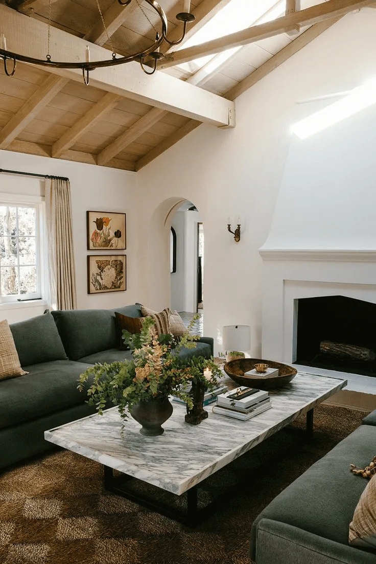 a Spanish-style house interior showing a living room with fireplace, arched doorway and wood ceiling beams