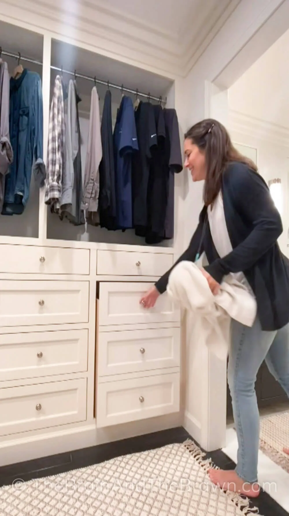 a woman pulling out a hidden hamper for laundry, white cabinets and drawers