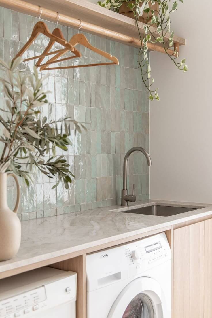 folding space in a laundry room on countertop with sink and tile backsplash 
