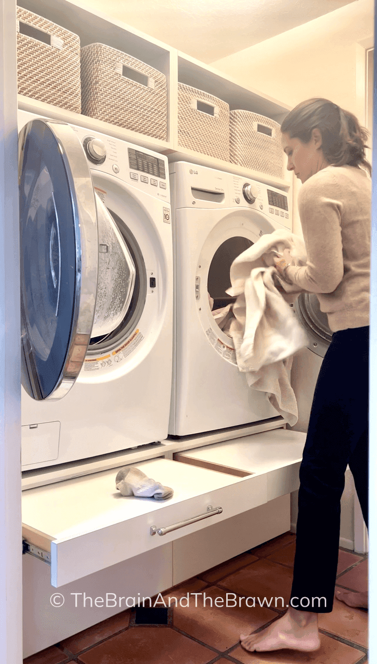 a raised washer and dryer with pull-out shelves and drawers below