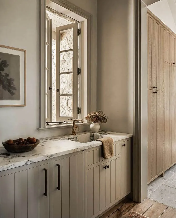 a calm laundry room with sink and cabinet storage in beige