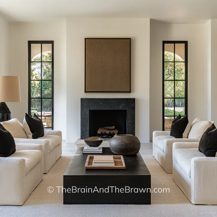 a neutral living room with four chairs and a fireplace, with a large dark rectangular modern coffee table 