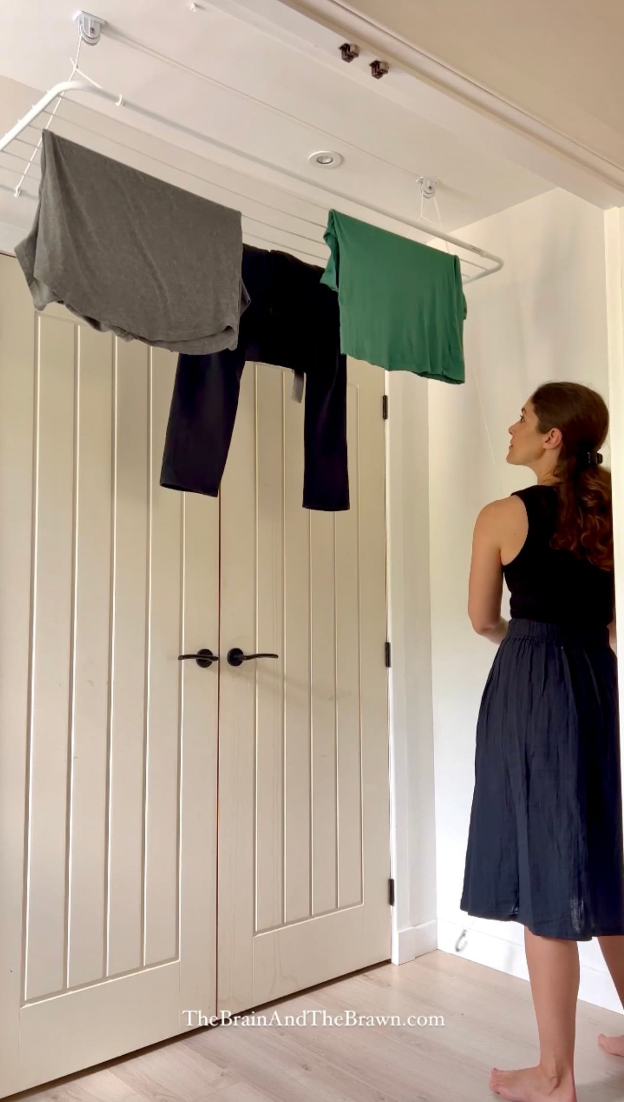 a ceiling mounted adjustable drying rack in a laundry room