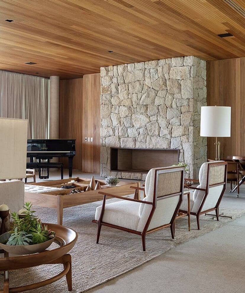 living room with stone fireplace and wood paneling in a mid-century modern style