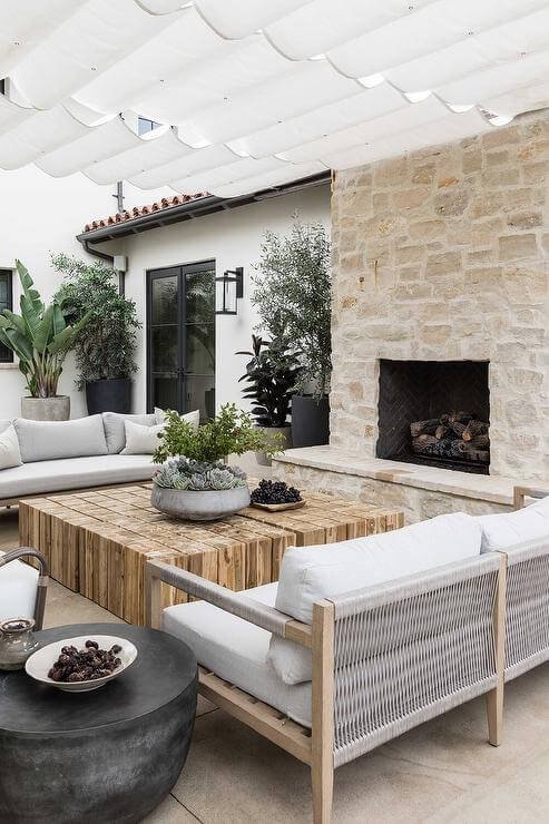 an outdoor stone fireplace sitting area with canopy