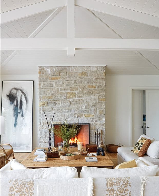 coastal stone fireplace in living room, white plank ceilings and beams
