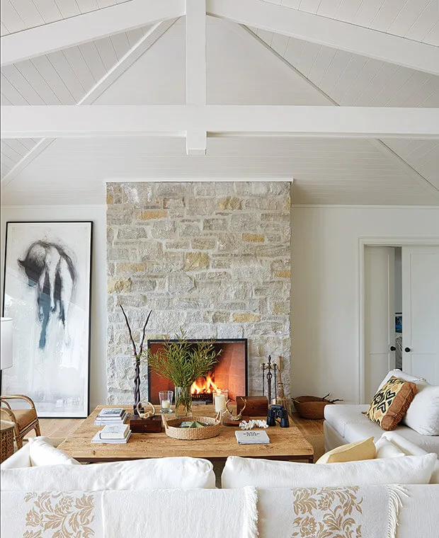 coastal stone fireplace in living room, white plank ceilings and beams