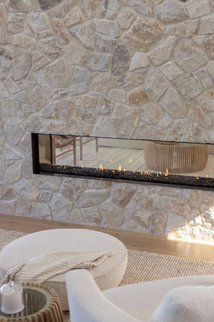 a modern gas stone fireplace double-sided between two rooms, no mantel