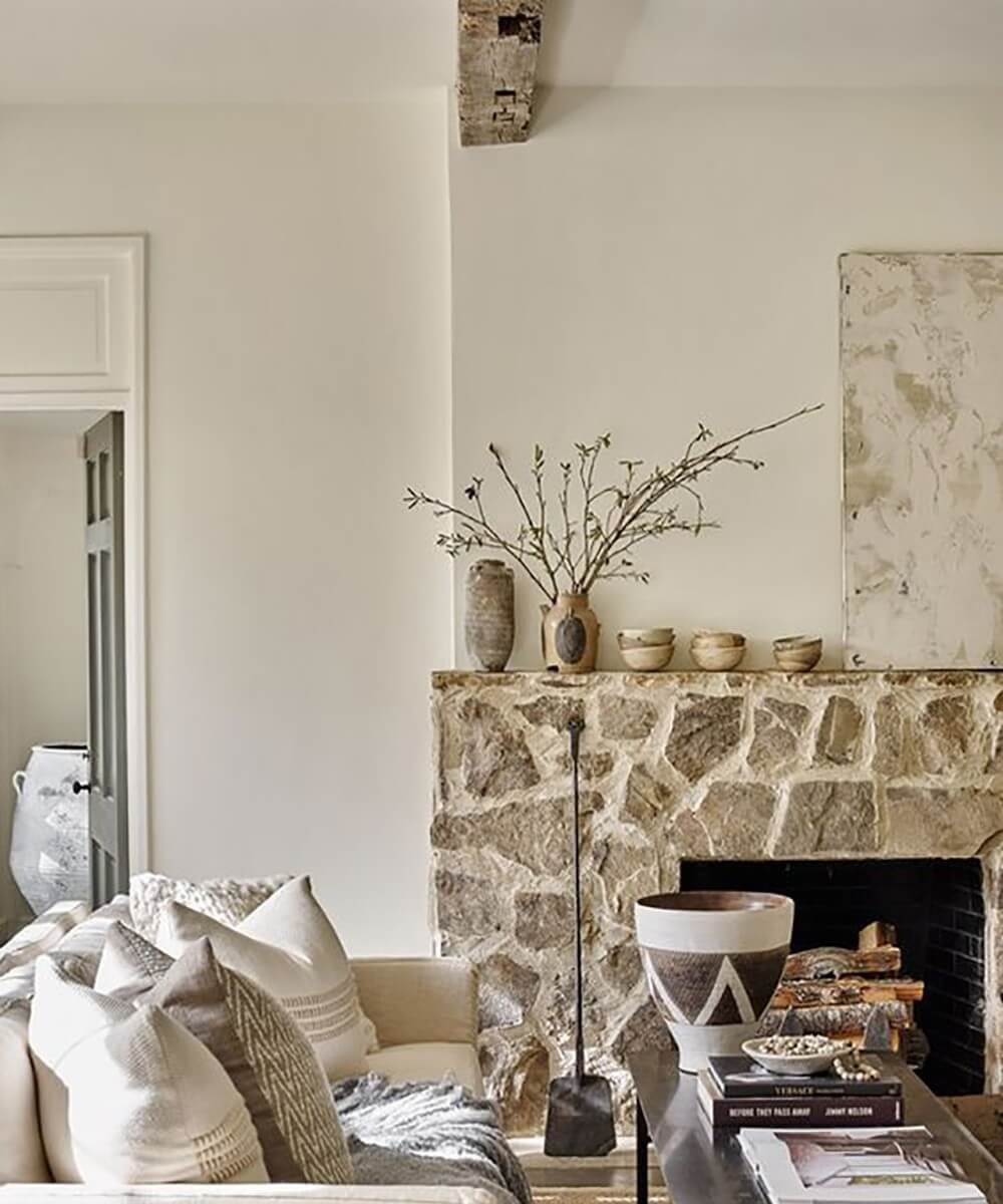 a beautiful natural stone fireplace going up half the wall in a living room
