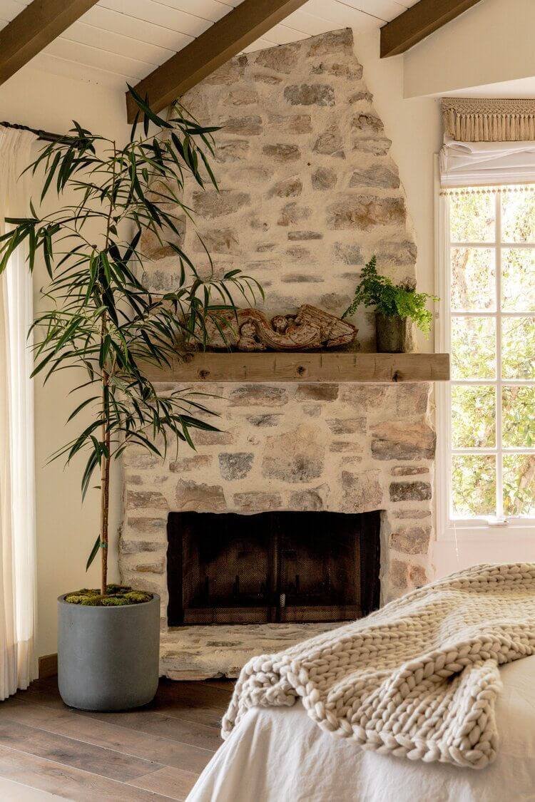 a German schmear or old world cottage-style stone fireplace with mortar over-grouted and a wood mantel