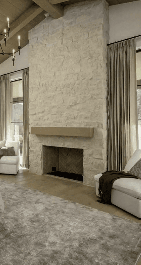 tall stone fireplace in living room or bedroom with a wood mantel surround